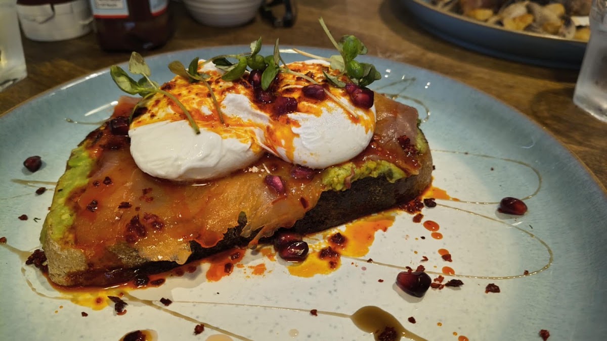 Poached eggs over smoked salmon and avocado on toast, with chilli oil, pomegranate seeds and micro herbs.